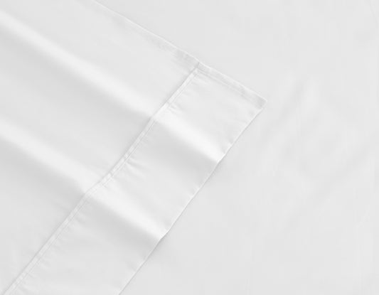 White cotton-rich sheet edge with visible stitching and hem