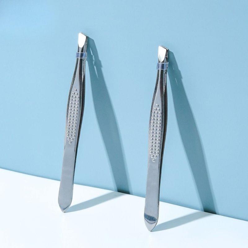 Pair of silver slant-tip eyebrow tweezers with textured grip, angled ends