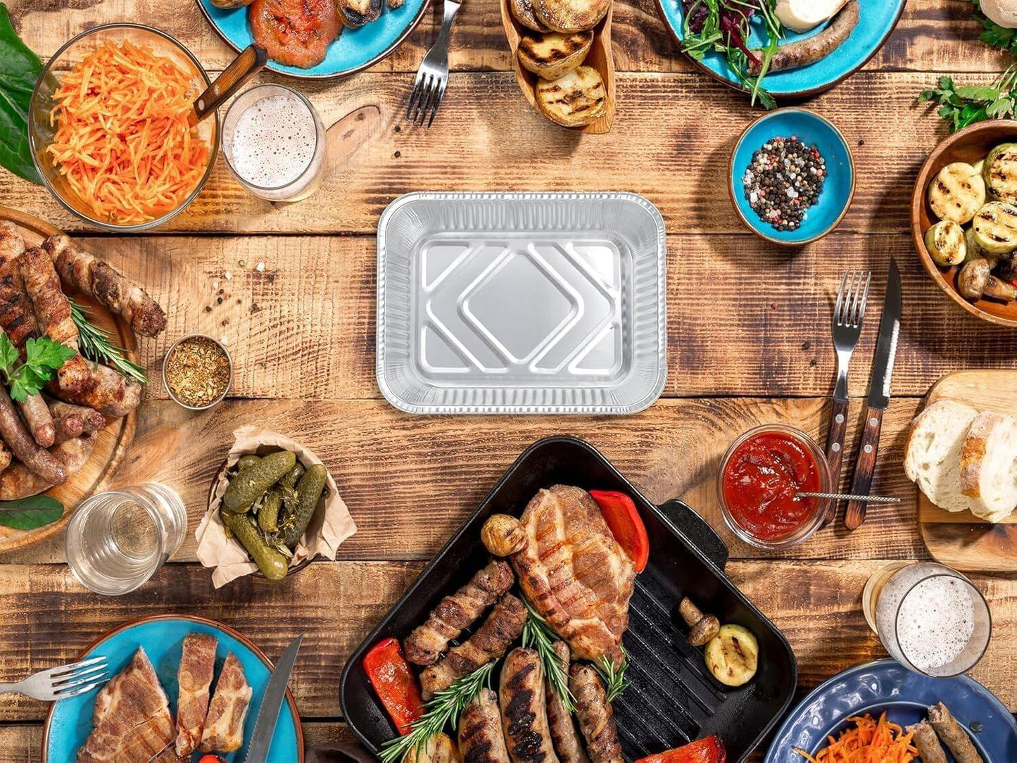 Aluminum foil food container with lid on table, surrounded by prepared foods