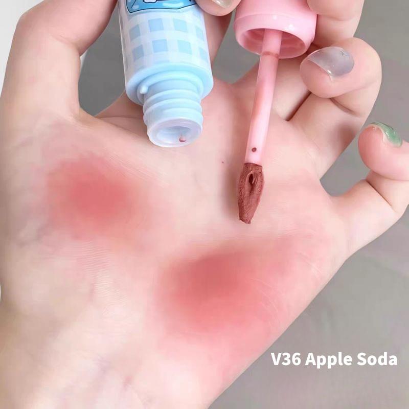 Lip mud applicator held over open palm beside light blue bottle and pink cap