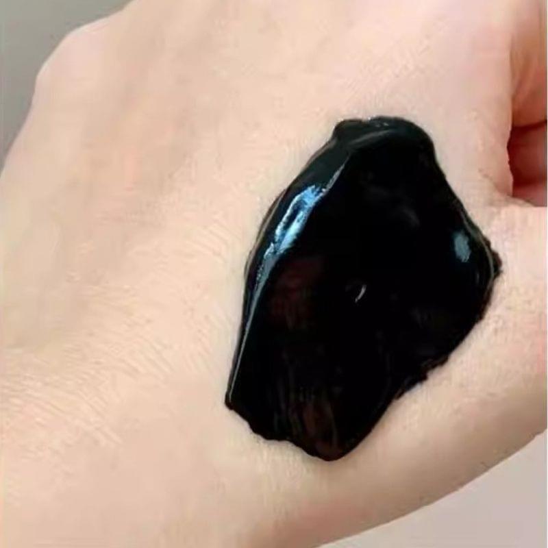 Glossy black face mask gel spread on skin, close-up