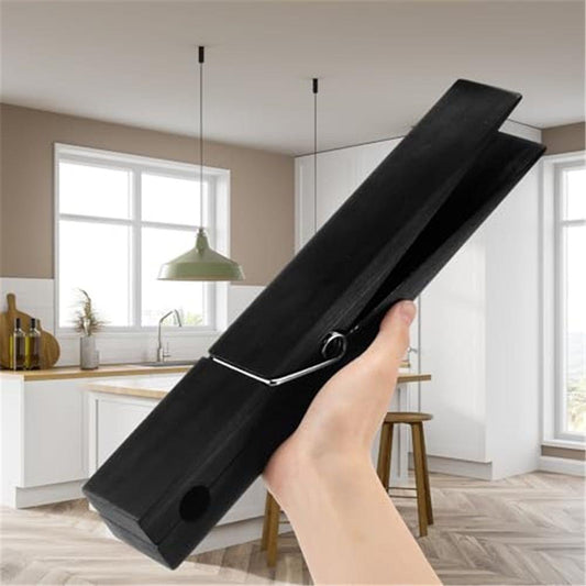 Black jumbo wooden clothespin with metal spring, held open for clamping laundry