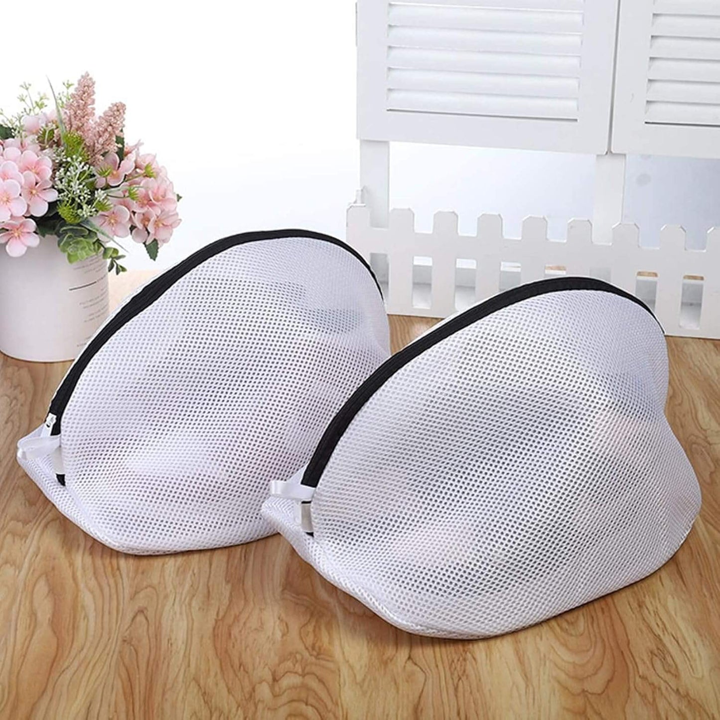 Two white mesh shoe wash bags with black edges, set on a floor