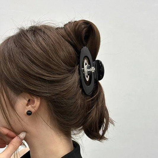 Medium hair claw clip with black oval acetate and silver diamond-style emblem centerpiece