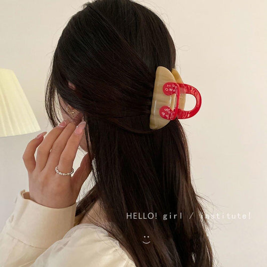 Beige hair claw clip with red numbered handle holding long dark hair