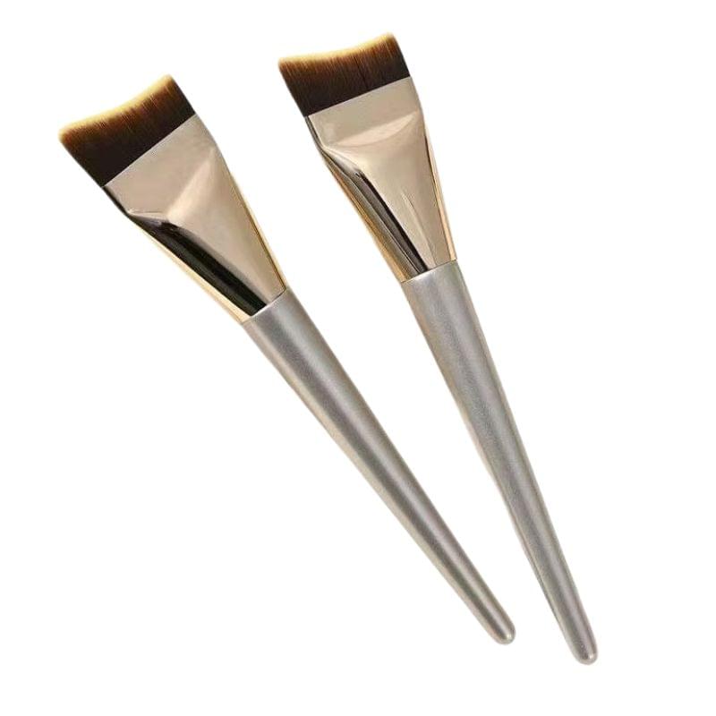 Two fishtail foundation brushes with silver handles and brown bristles, angled