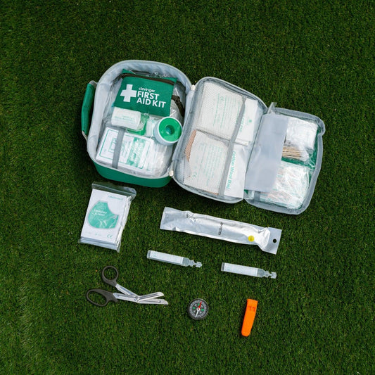 Open first aid kit with gauze, scissors, thermometer, and round compass