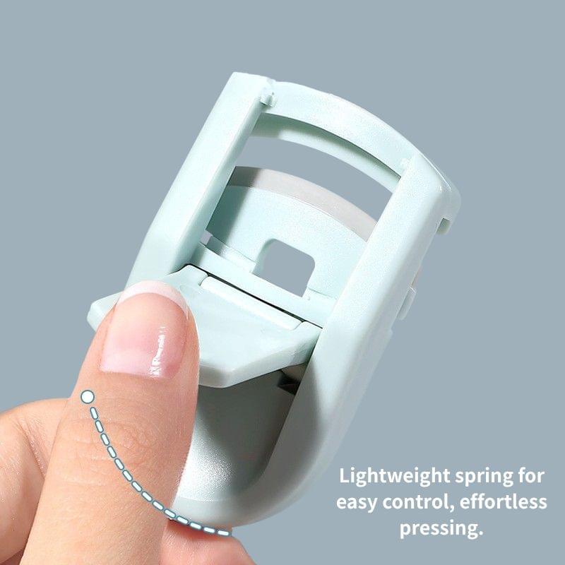 Close-up mini eyelash curler with open clamp, held by fingers for pressing