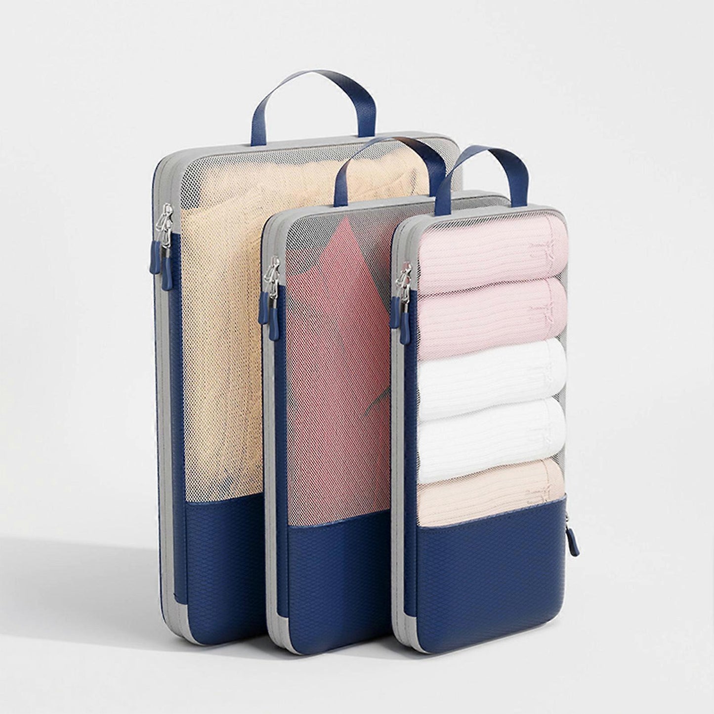 Three compression packing cubes with top handles, blue edges, sand and pink panels