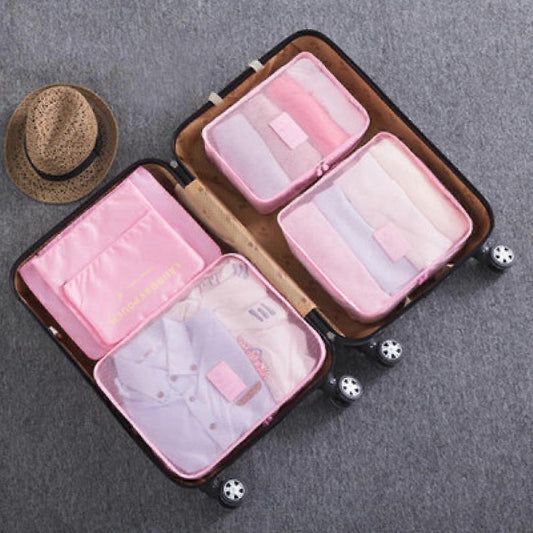 Pink packing cubes inside suitcase with zip compartments and mesh panels.