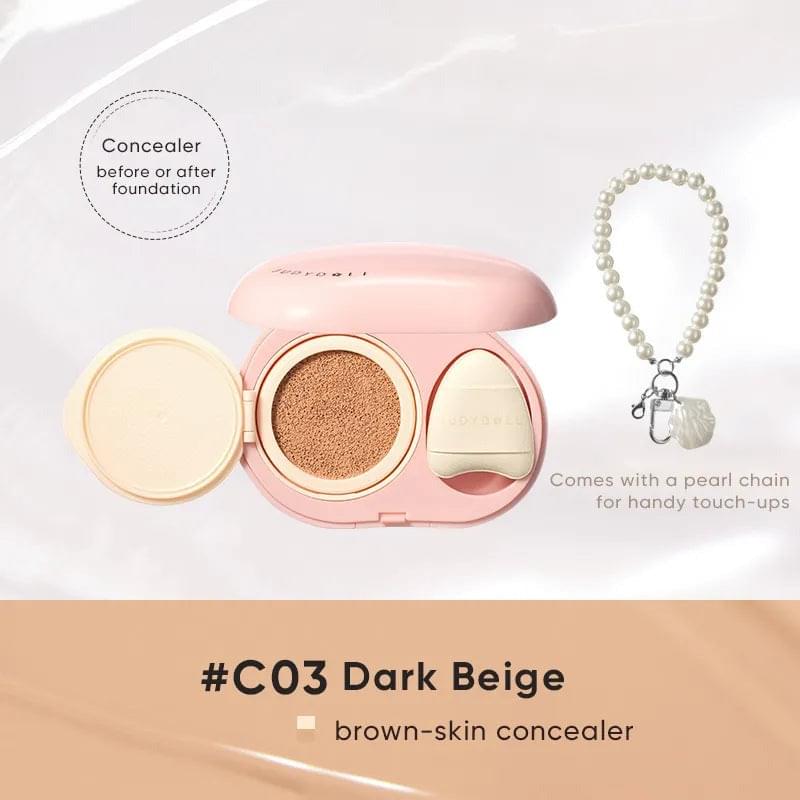 Pink cushion concealer compact, dark beige base, includes pearl chain for touch-ups
