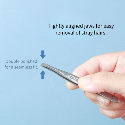 Silver slant-tip eyebrow tweezers held in hand, pointed stainless tool for removal
