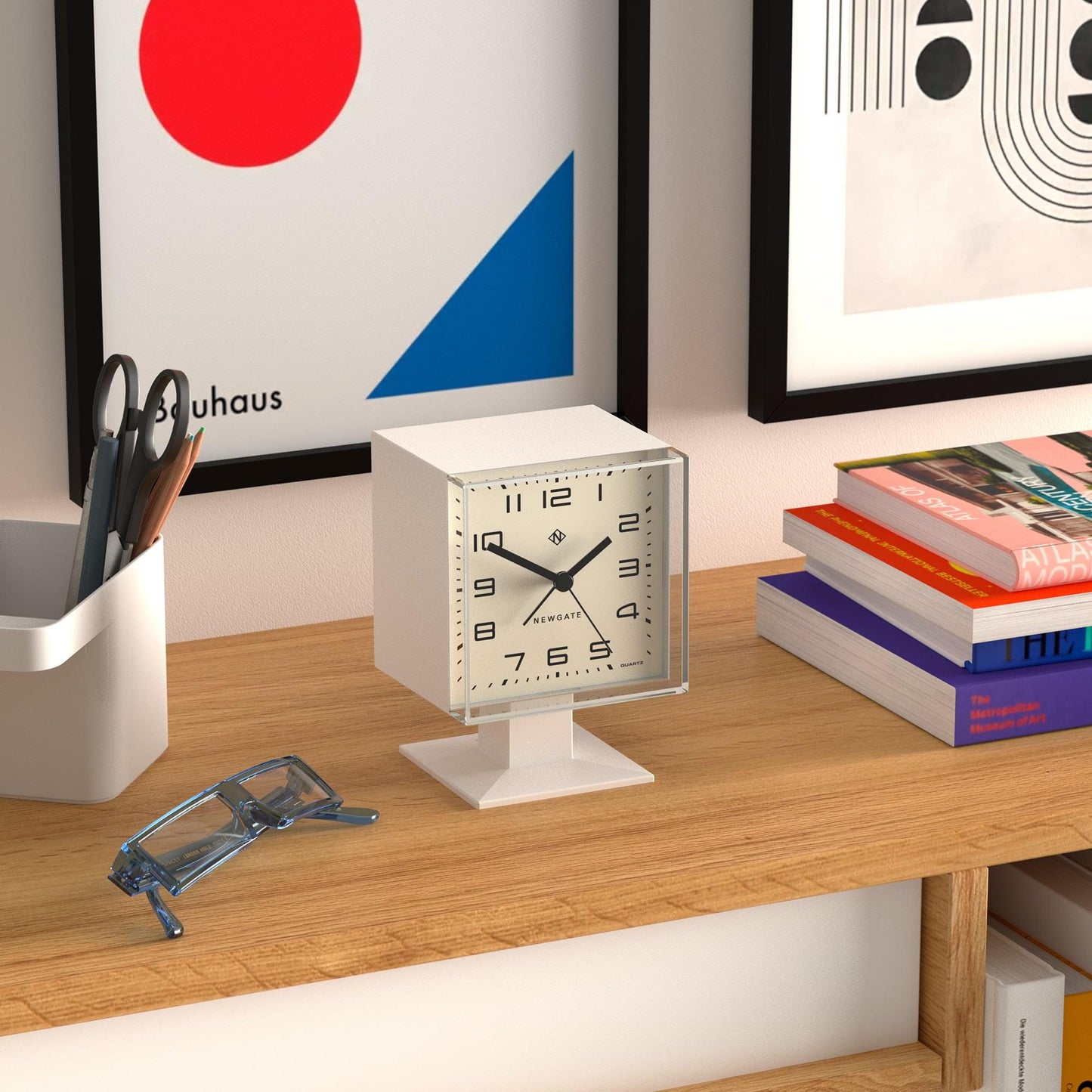 White square alarm clock on a desk stand, with black hands and numbered dial