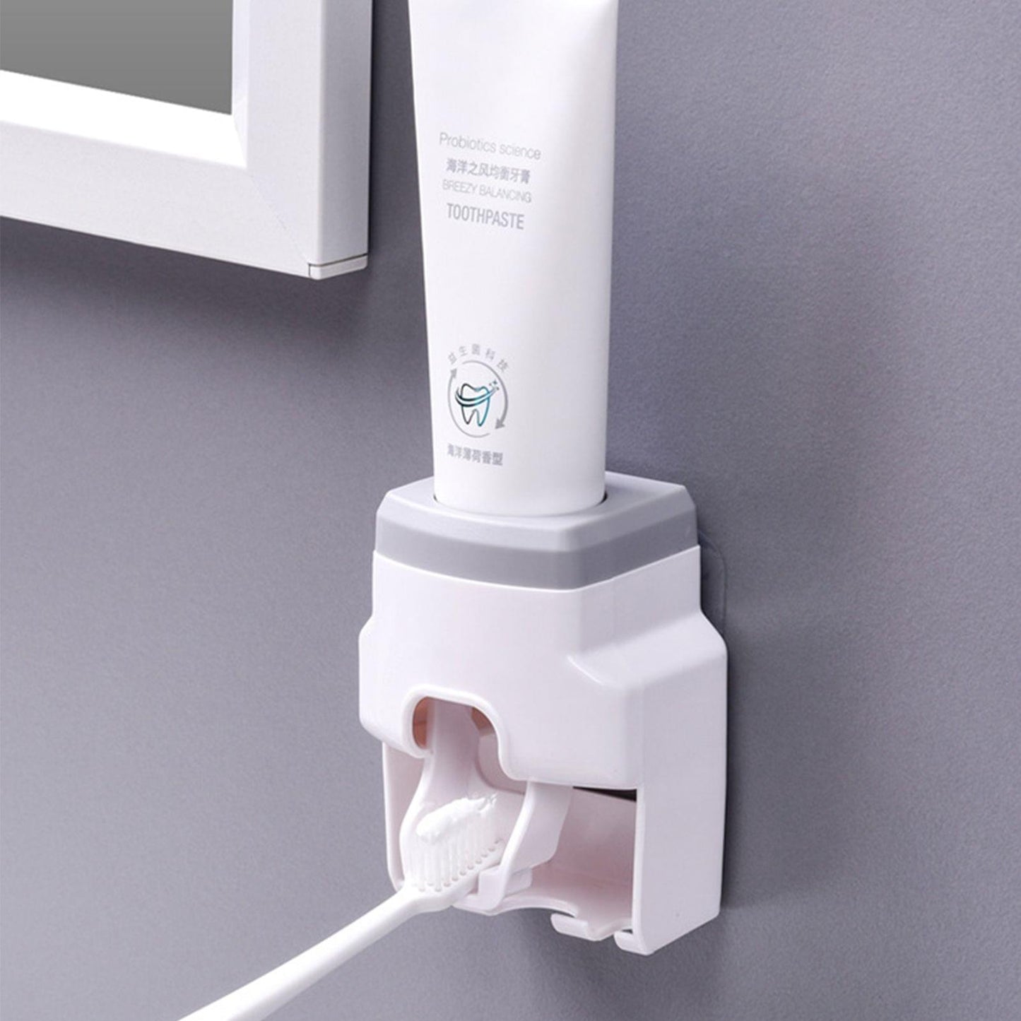 Wall-mounted toothpaste dispenser with toothbrush holder and squeeze lever, white and grey