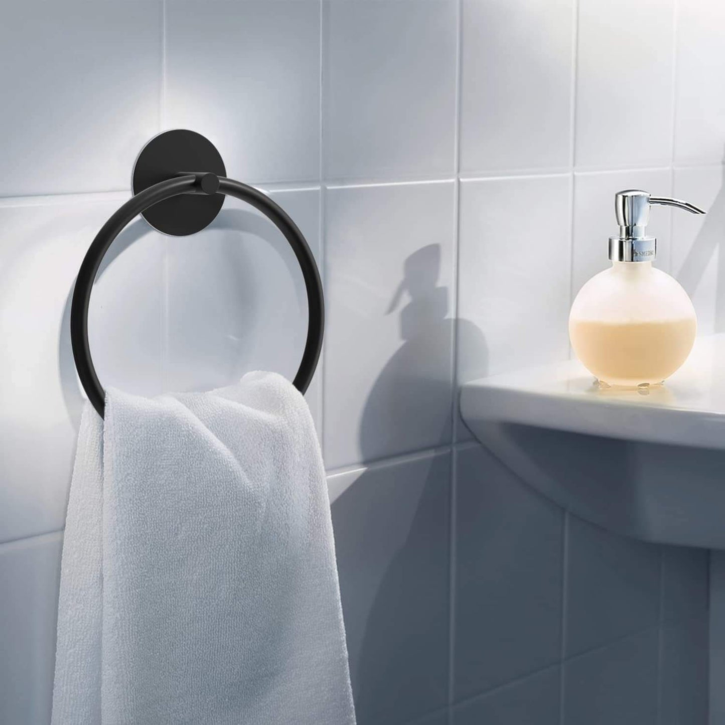 Black towel ring holding a folded hand towel on a wall-mounted base