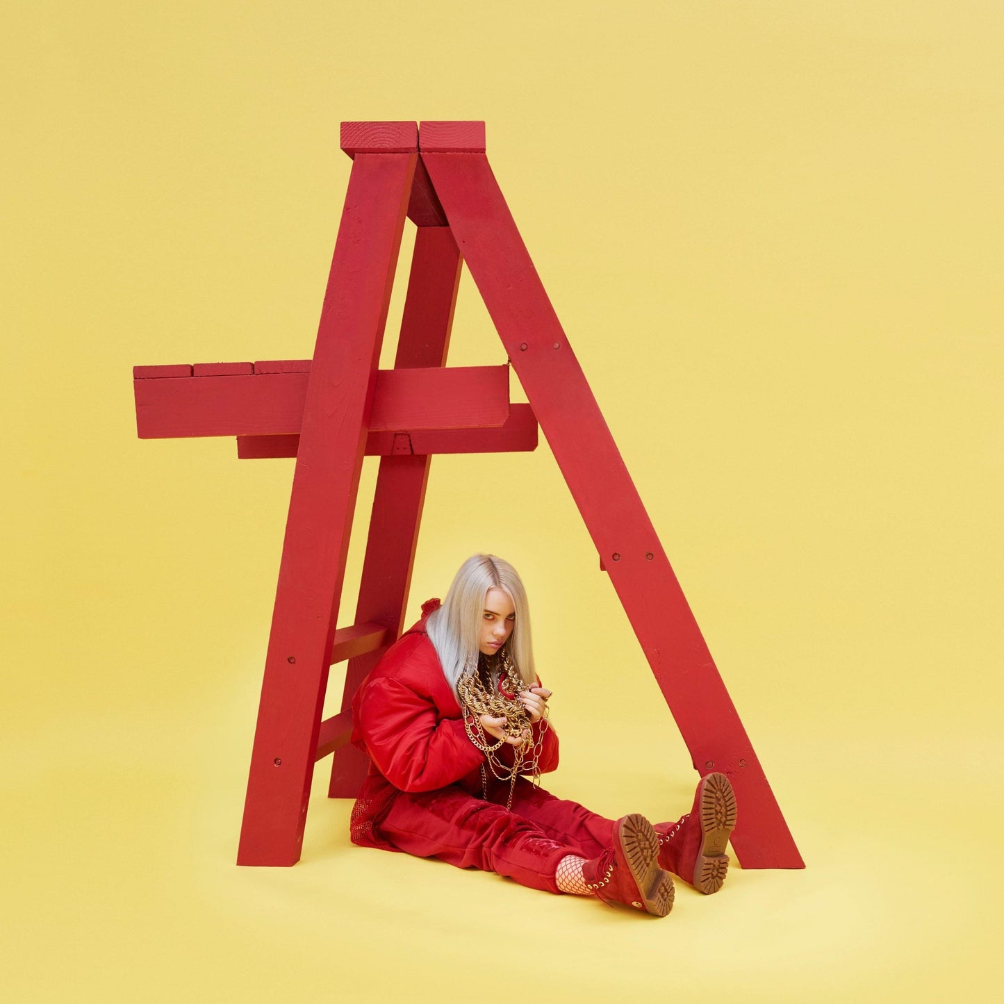 Album cover with Billie Eilish in red outfit beside large red A frame.