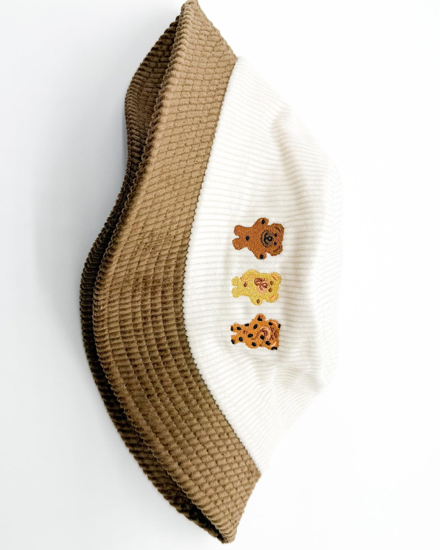 Two-tone bear bucket hat with white side panel and brown brim, showing bear patch detail