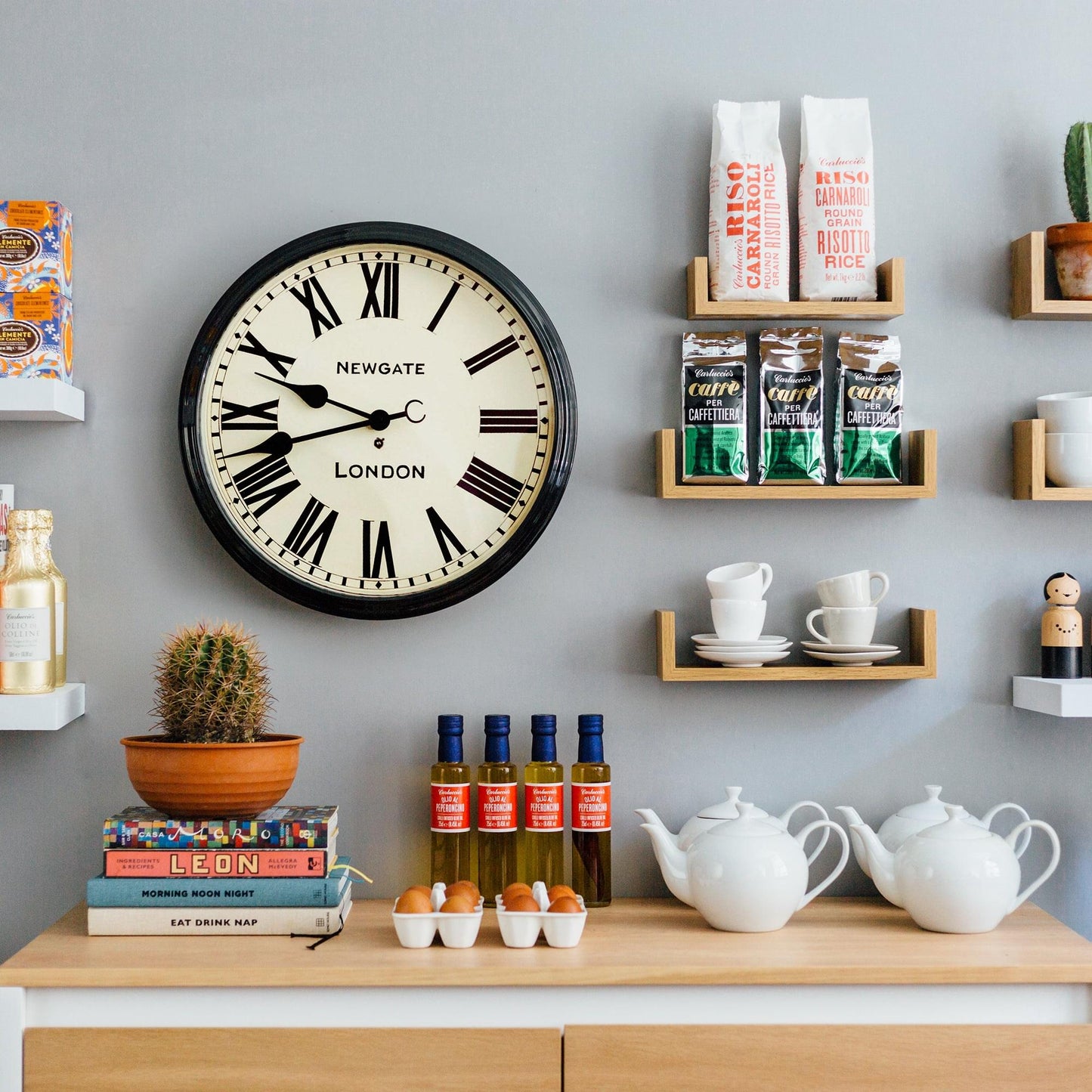 Black wall clock with roman numerals and Newgate London lettering mounted on wall.