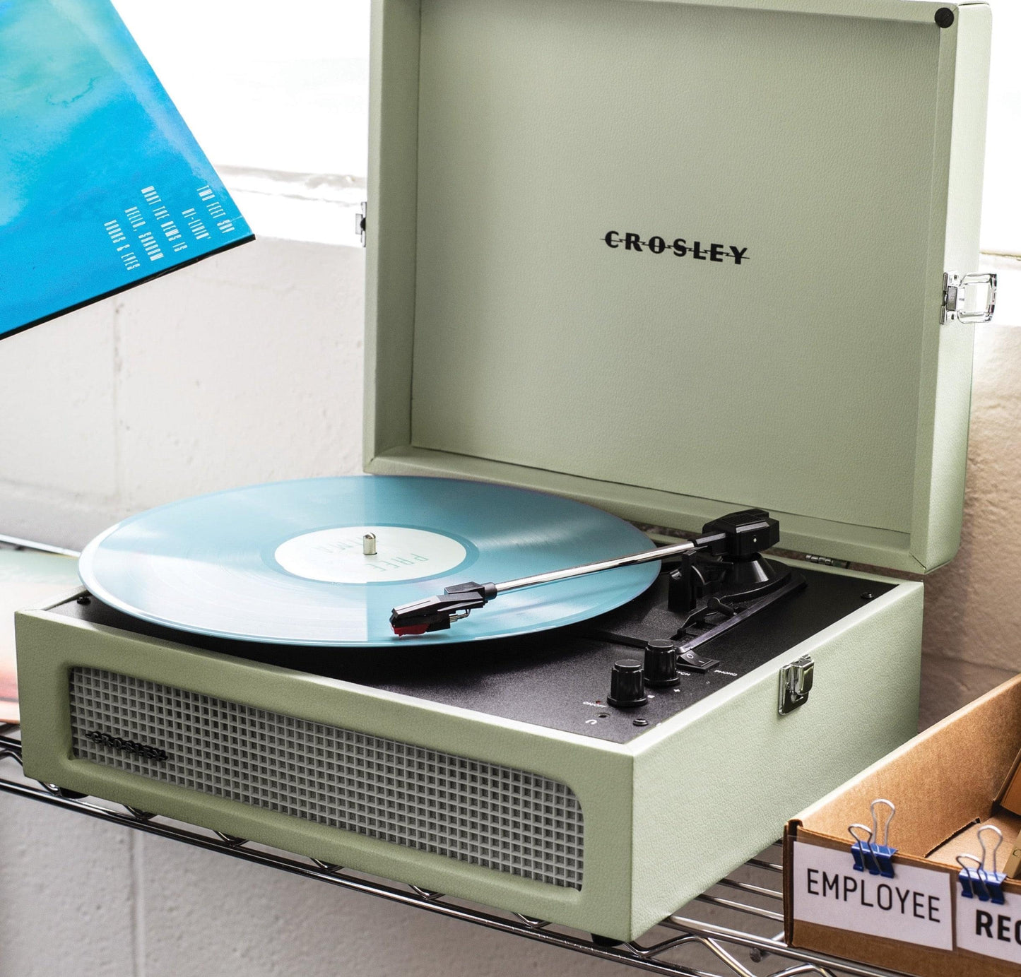 Sage portable Bluetooth turntable with light-blue vinyl record on platter, lid open