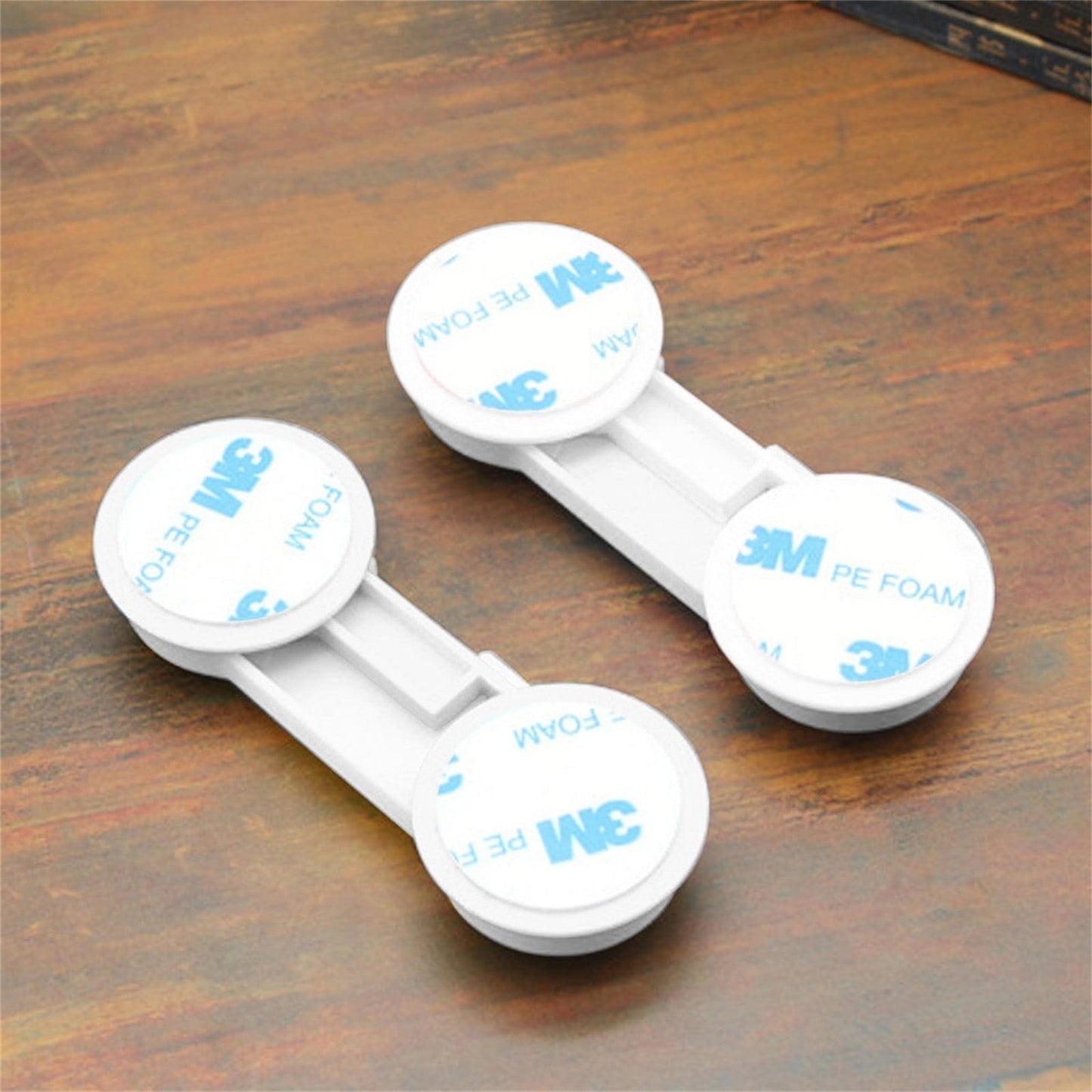 Plastic cabinet lock with two white adhesive pads marked 3M