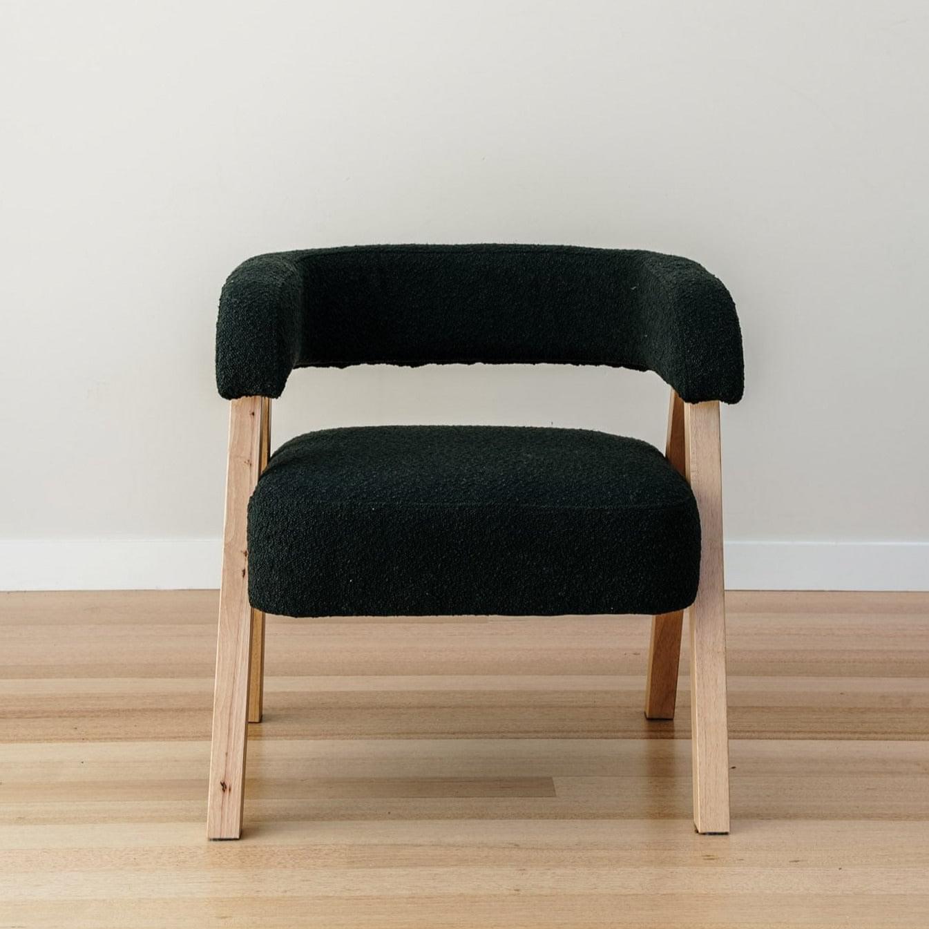 Boucle accent chair in dark charcoal with rounded arms and light wood legs