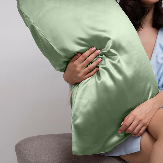 Sage green satin pillowcase held against chest, smooth sheen fabric