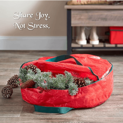 Red round wreath storage bag with handles, holding a wreath