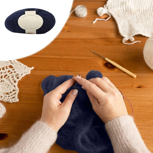 Navy yarn skein with cream label during knitting, with hands and tools