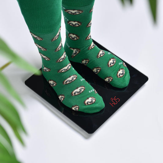 Digital bathroom scale with green patterned socks on black glass platform