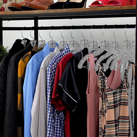 Set of crystal-clear plastic hangers with metal clips holding shirts and dresses
