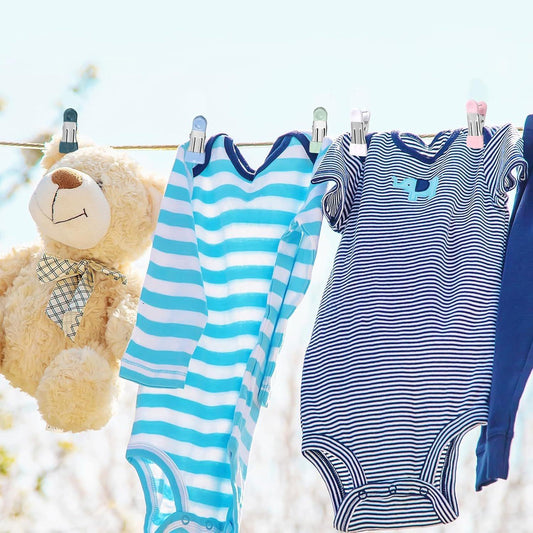 Clothespins holding striped baby clothes on a clothesline with blue clips
