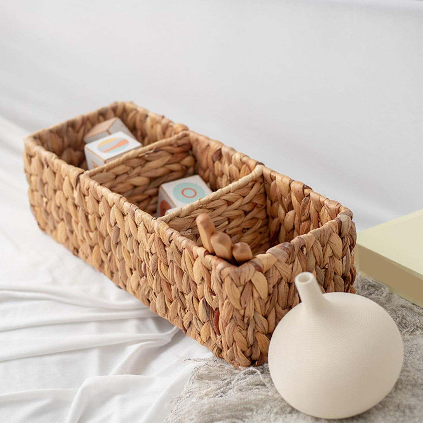 Khaki woven basket with open top and small toys inside, rope weave with inner divider.