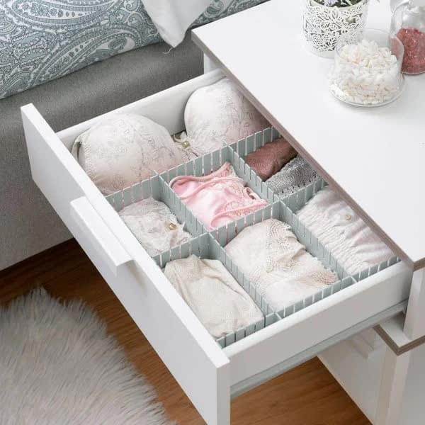 Drawer organizer with light gray dividers separating folded linens and garments