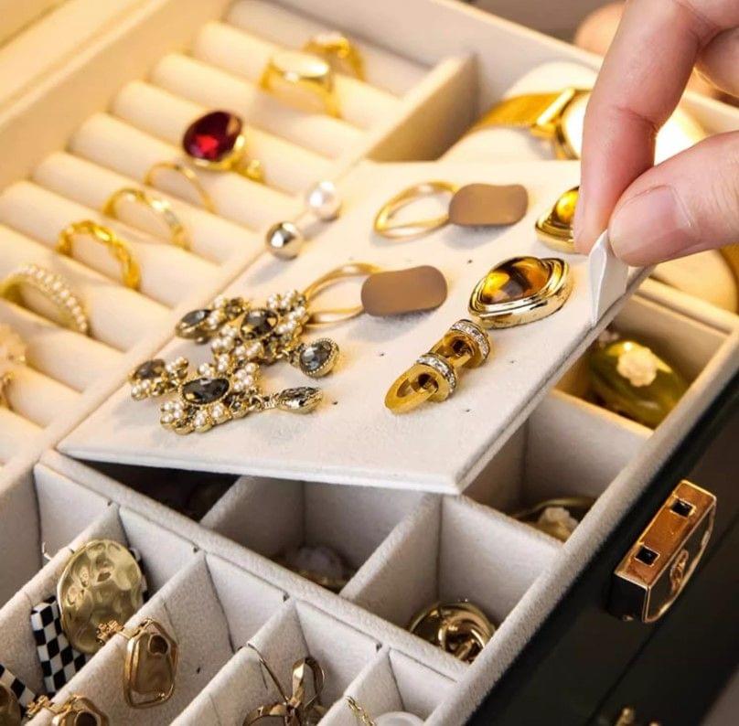 Close-up of jewelry in dark green organizer box, rings and earrings in compartments.