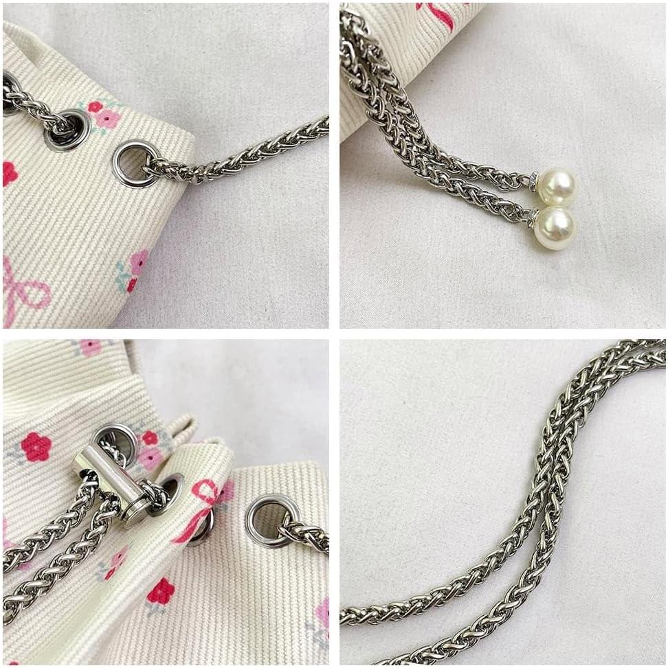Close-up of cream bag hardware: silver chain, clasp ring, and pearl bead dangles