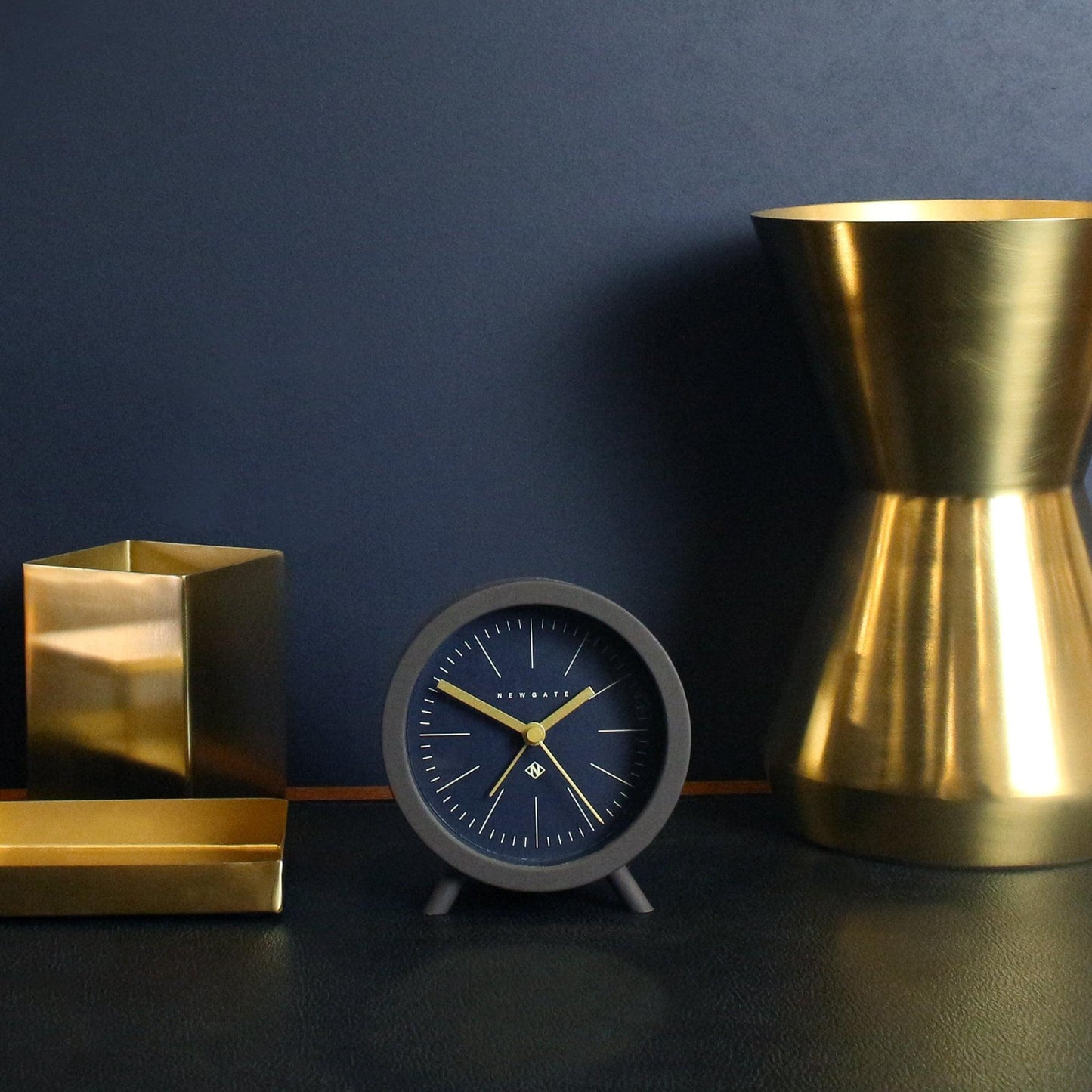 Dark blue alarm clock with gold hands in black frame, reverse-dial face
