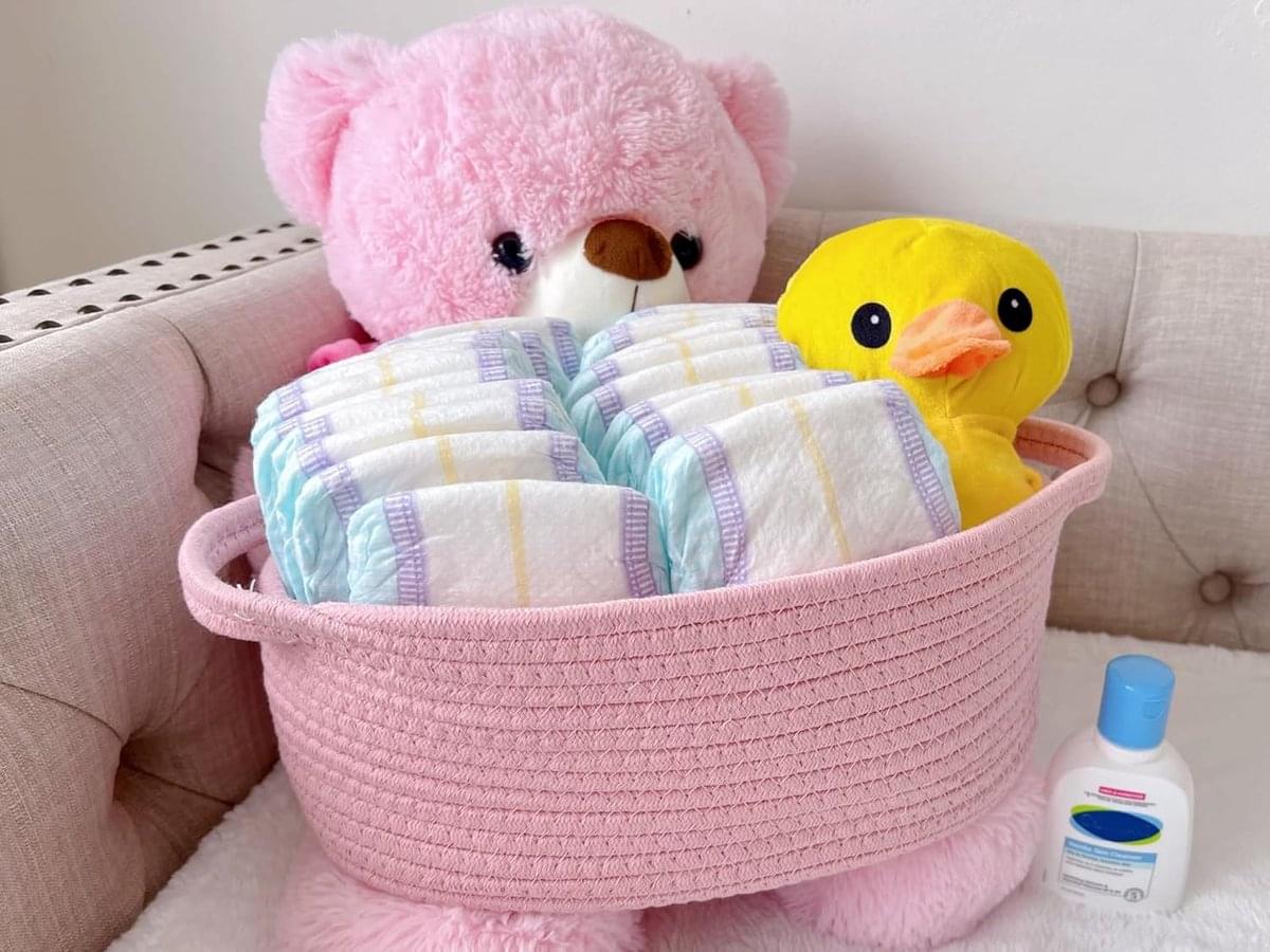 Pink woven rope storage basket with handles, holding plush toys on sofa