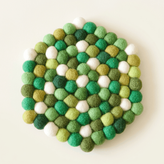 Round wool felt heat mat with green, white, and gold felt ball pattern