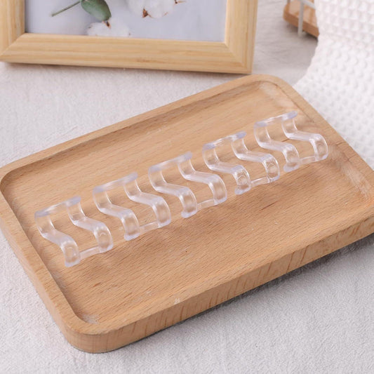 Clear hanger connector hooks laid out on a wooden base, curved connector clips