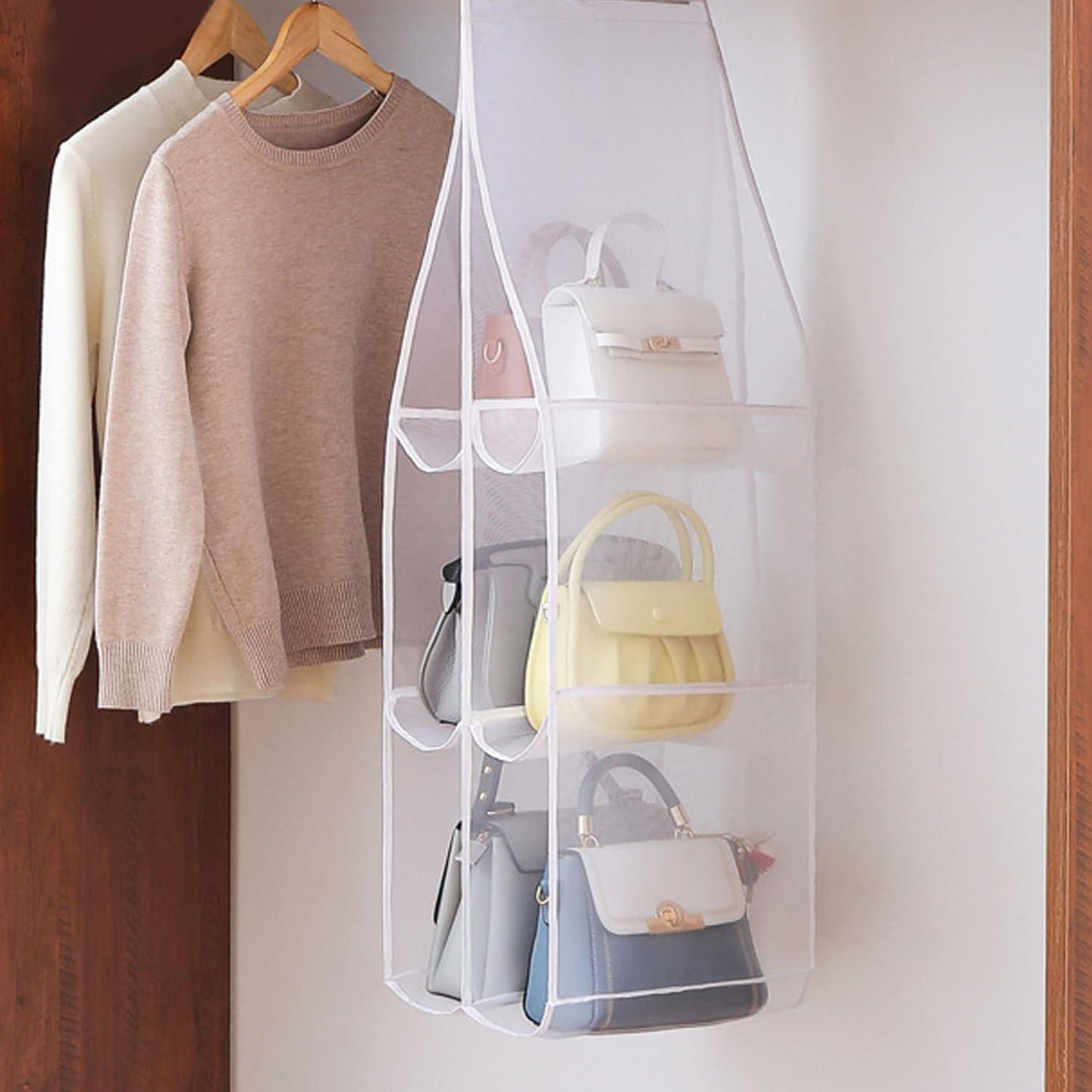 Transparent hanging handbag organizer with white trim, multiple pockets for handbags