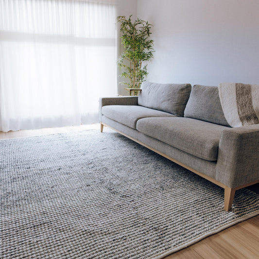Rectangular handwoven floor rug in light grey tones with looped grid weave