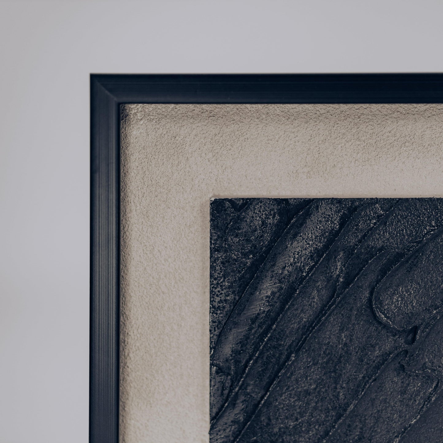 Close-up of framed dimensional sand art corner with raised dark ridges in sand.