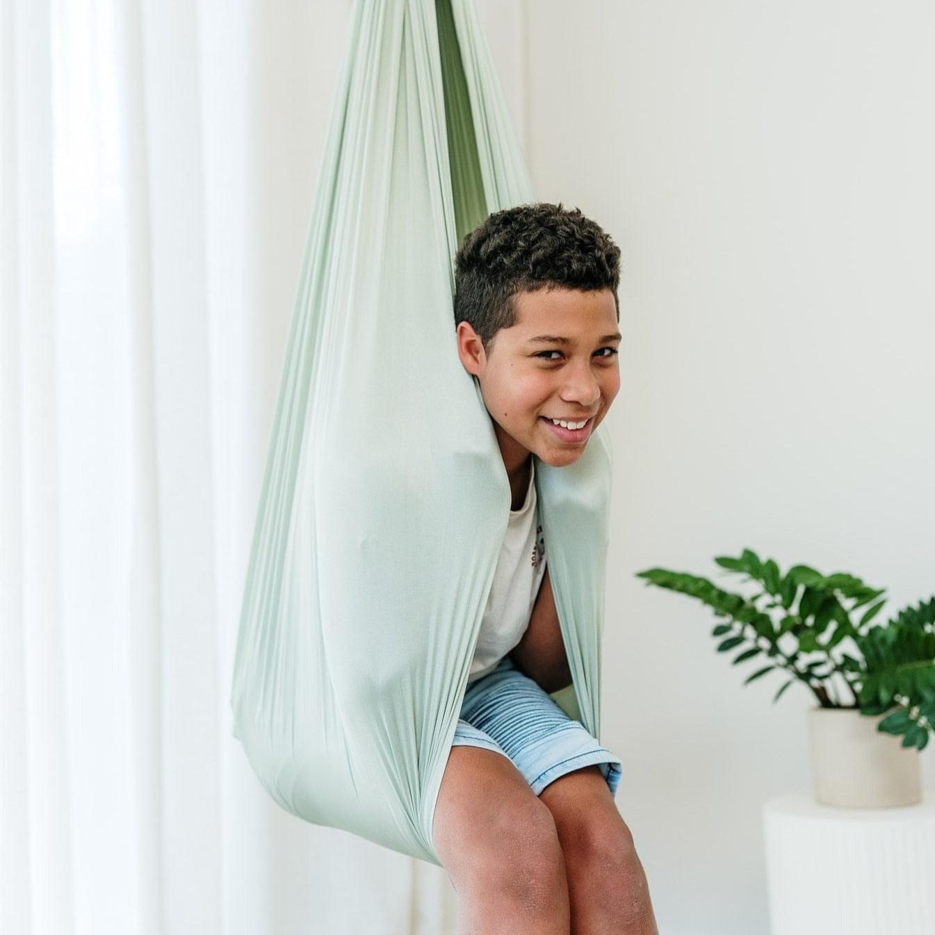 Sage green hammock cocoon swing with open side, person reclining on seat