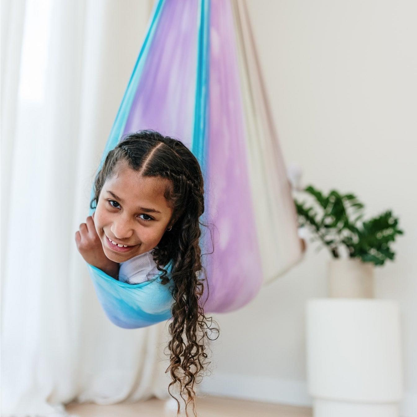 Rainbow tie-dye hammock cocoon with child peeking out, pastel stripes