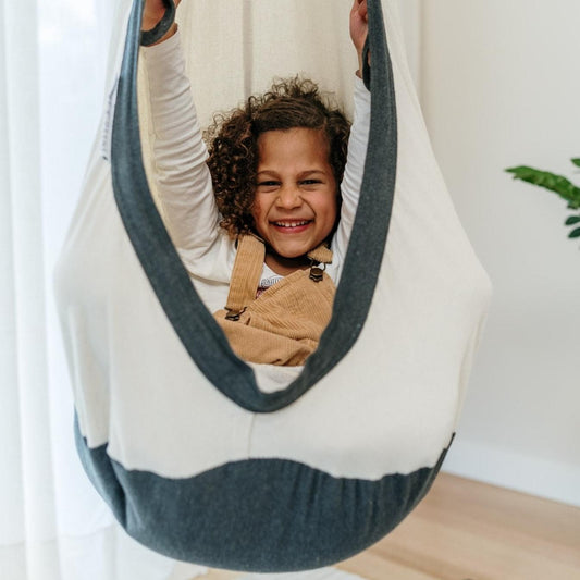 White cocoon swing with charcoal edge, child sitting inside