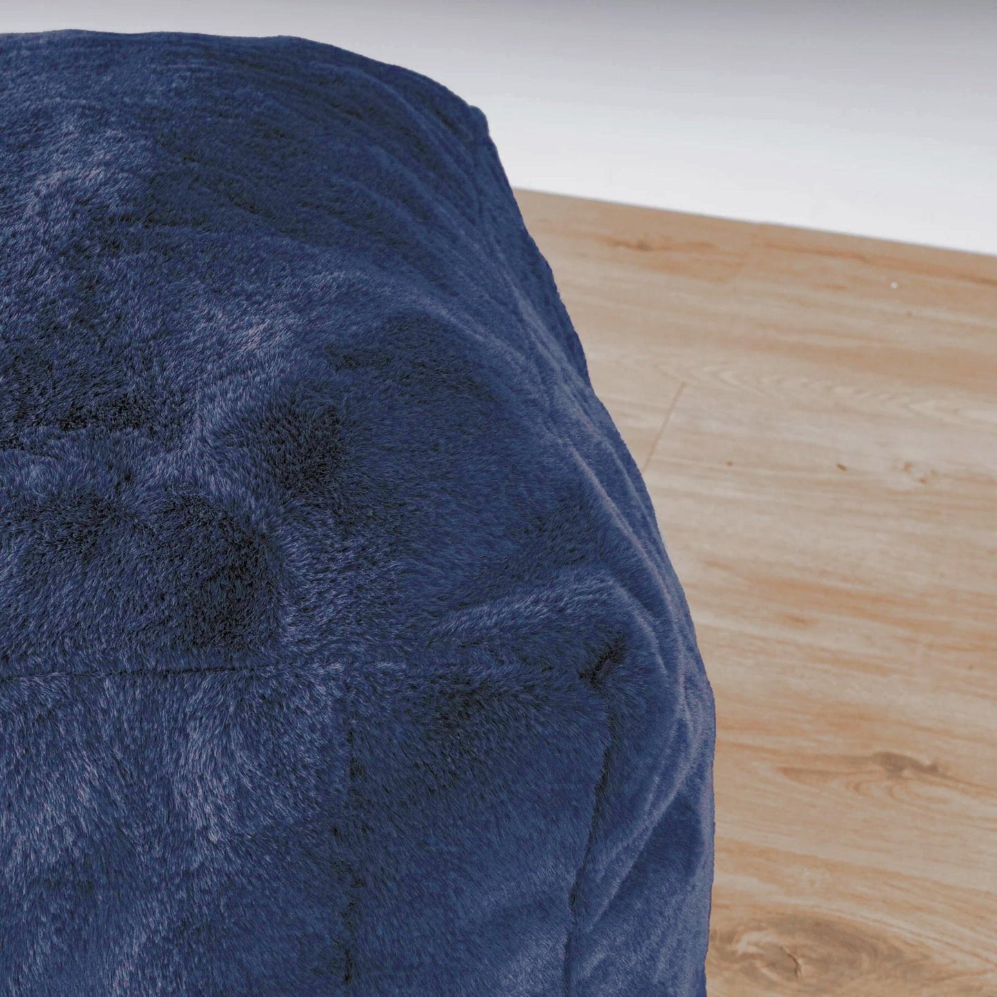 Close-up of navy blue plush ottoman upholstery with visible stitched seam
