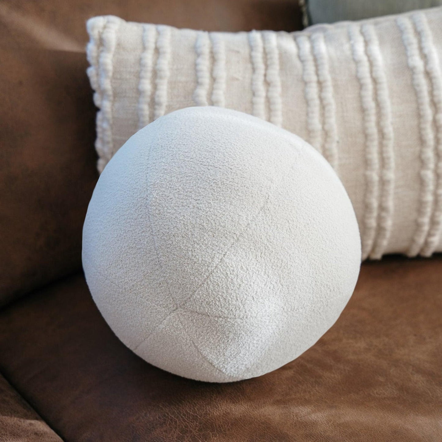 White round boucle ball cushion close-up with textured fabric and seam stitching