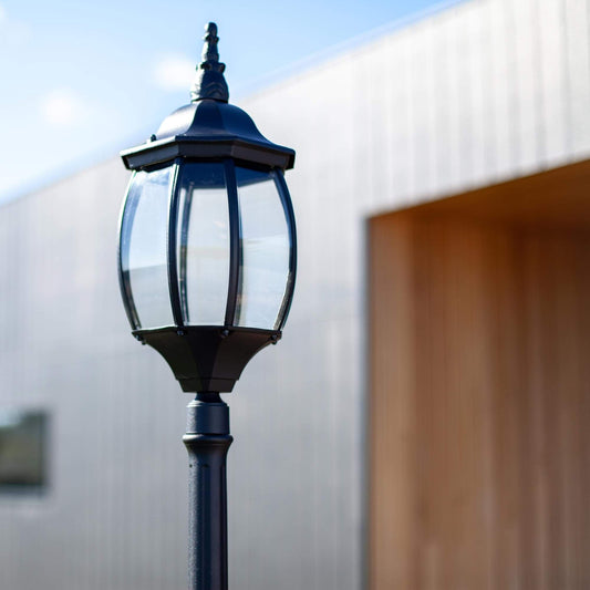 Close-up of black lantern lamp post with curved glass panels and decorative crown.