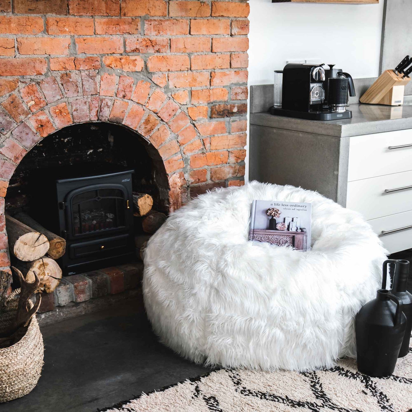 White faux fur bean bag with small decorative tray near fireplace