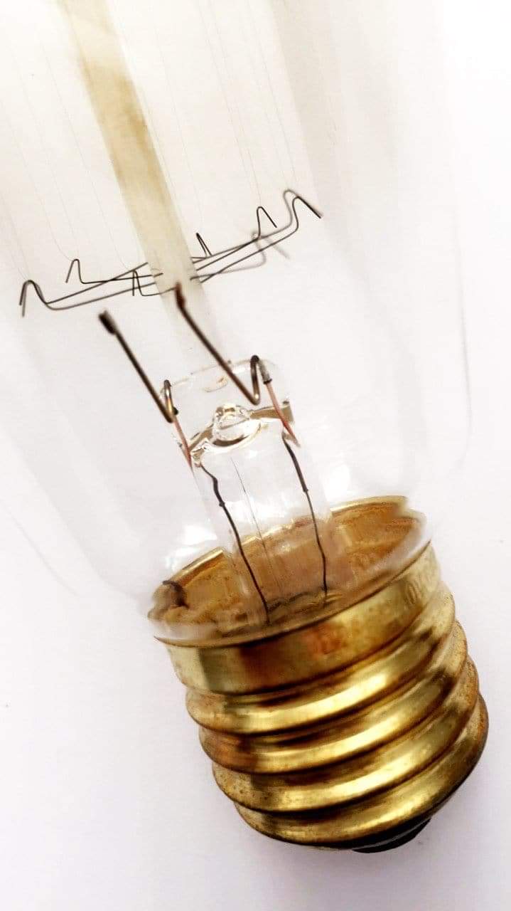 Edison filament light bulb close-up, clear glass with warm filament and gold screw base